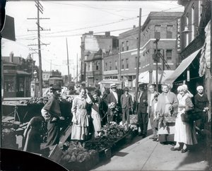 Compradores reunidos pela calçada produzem fora da mercearia Theodore Prieshoff, em 1929, na East Grand Avenue, perto da torre de água da Grand Avenue
